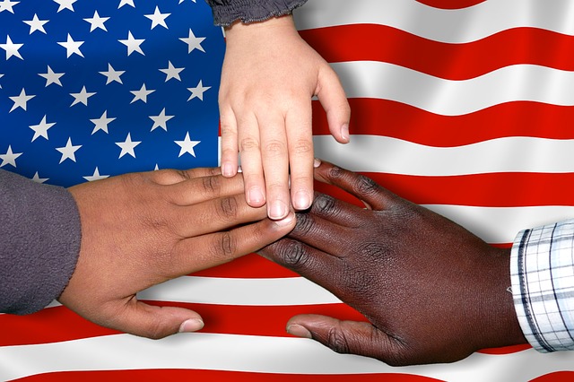 Black, brown, and white hands over American flag